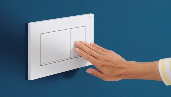 Hand triggers a flush on the white Sigma20 actuator plate (© Geberit)