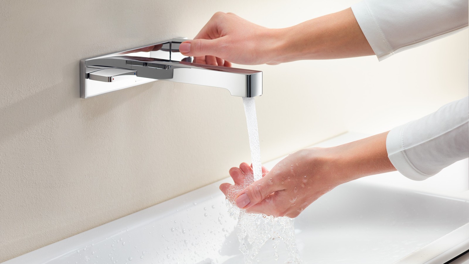 A woman turns on the tap and tests the intensity and temperature of the water jet (© Geberit)
