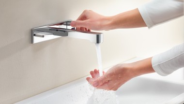A woman turns on the tap and feels the power and temperature of the water