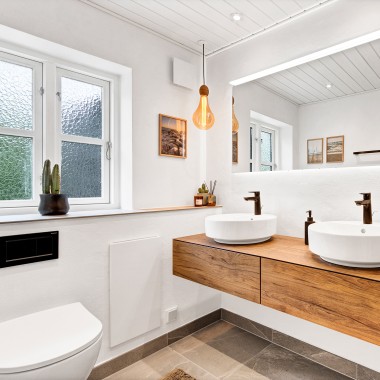 Bright, renovated bathroom with two round washbasins, a large mirror and wooden bathroom furniture (© @triner2 and @strandparken3)