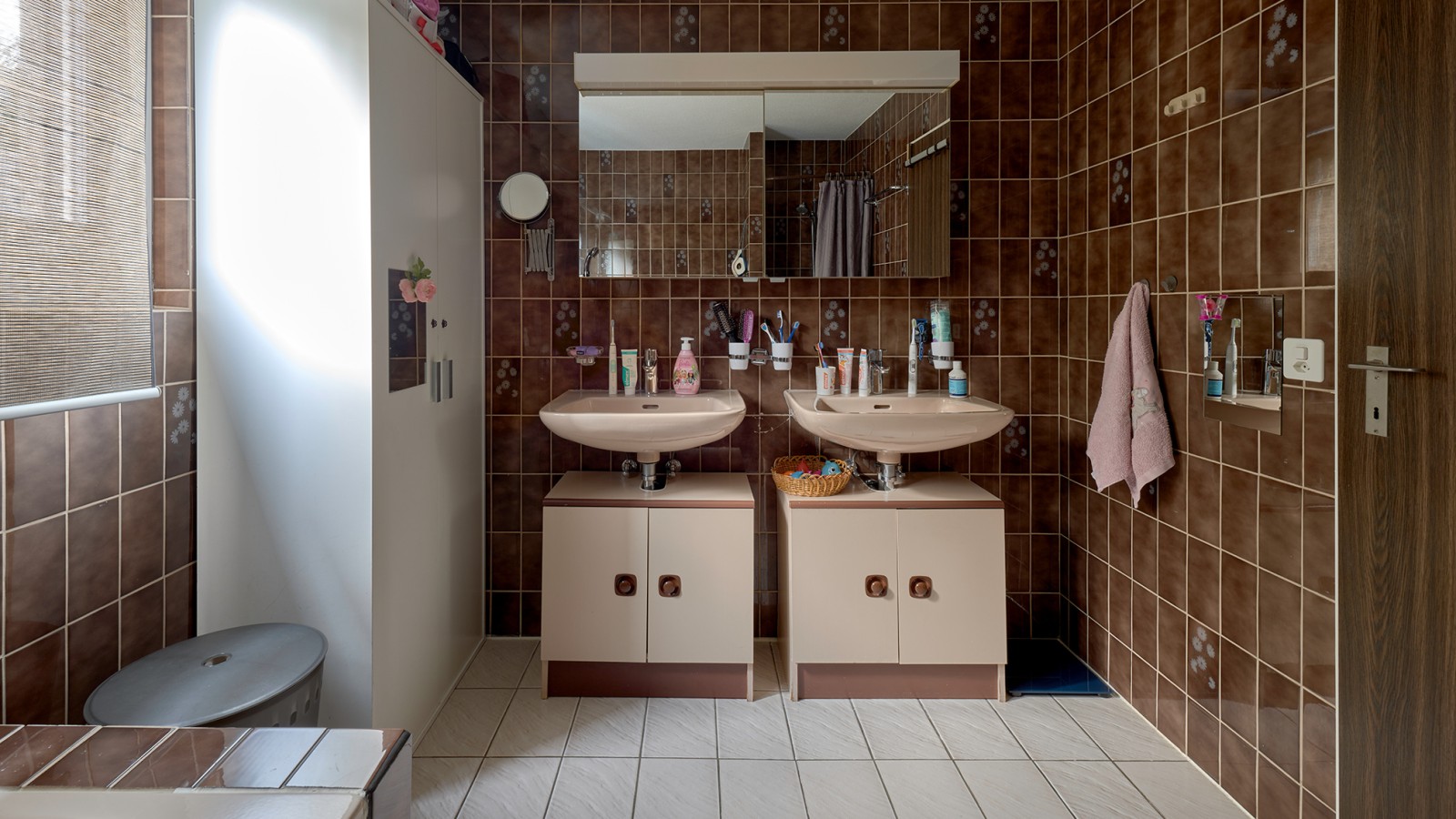 Bathroom with brown tiles and two washbasins