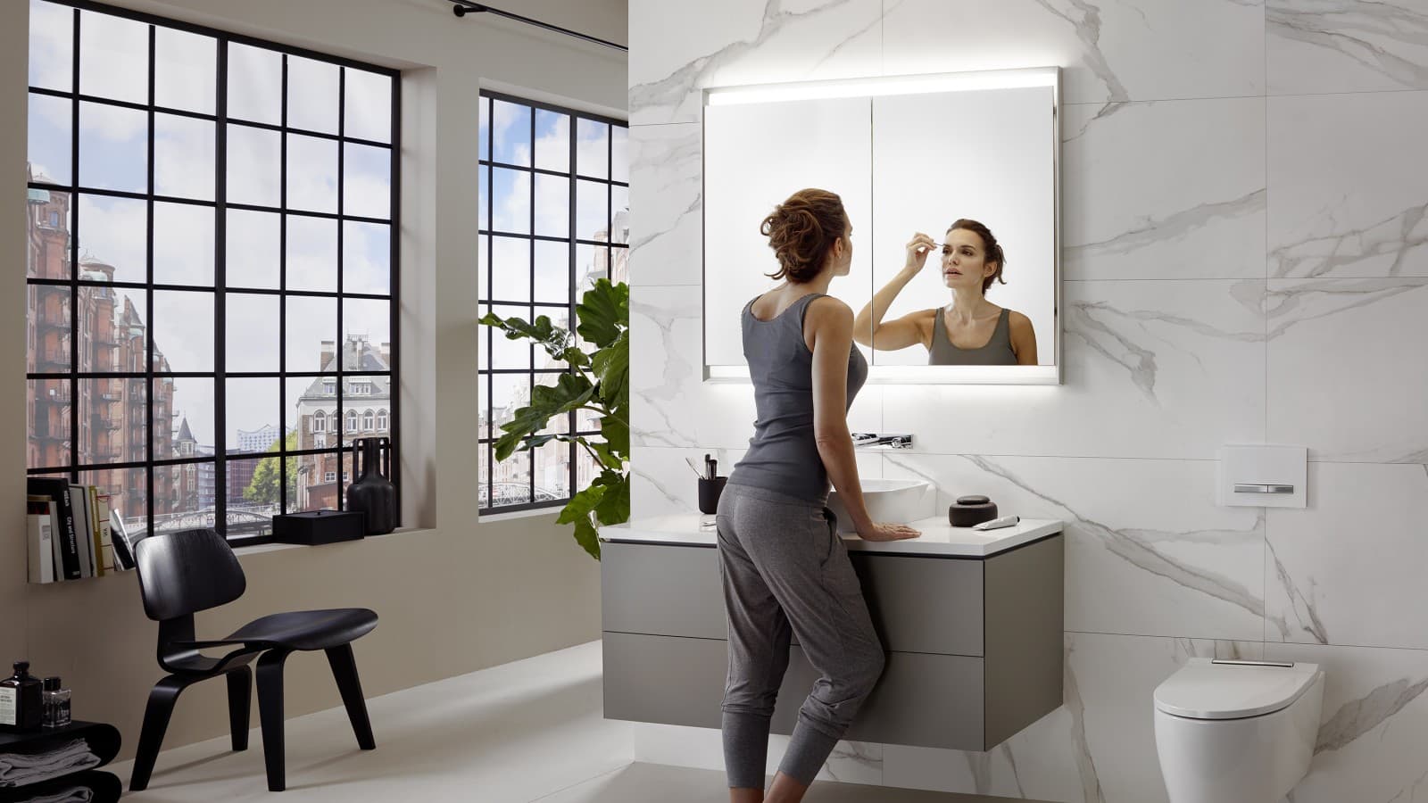 Woman standing in a Geberit ONE bathroom, with the washbasin mounted at the perfect height. Woman standing in a Geberit ONE bathroom, with the washbasin mounted at the perfect height.